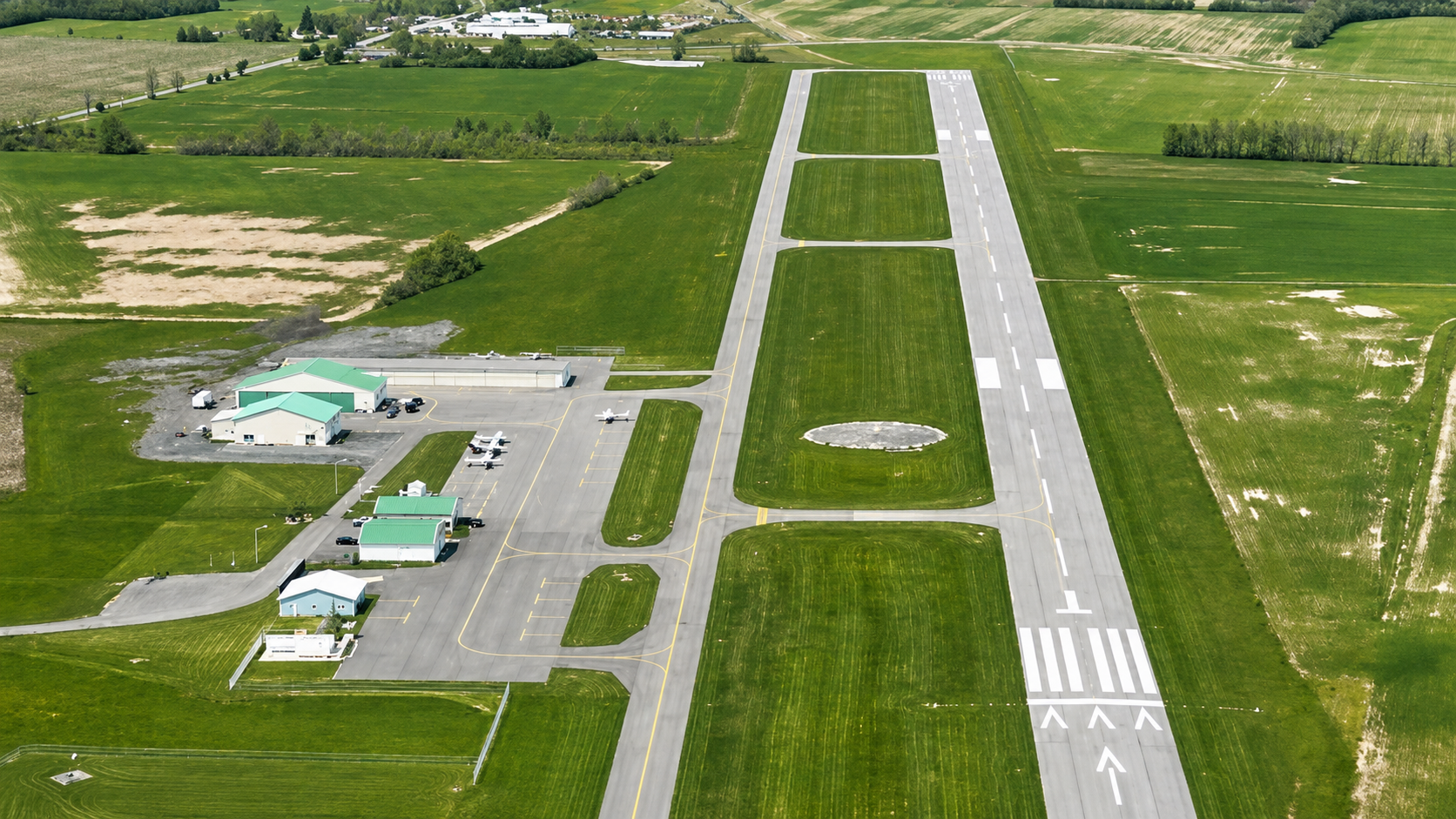 Aerial view of Finger Lakes Regional Airport runway 1/19 with hangars, ramp and surrounding farm fields